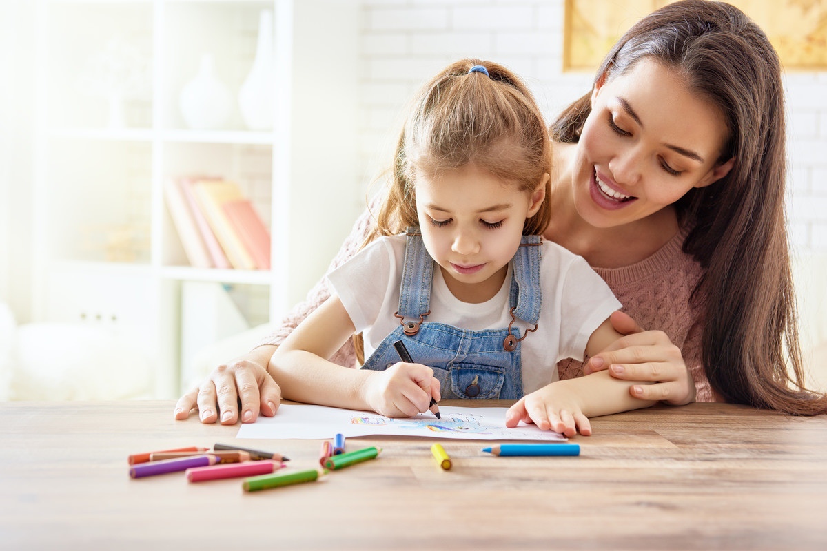 塗り絵をする子供と一緒に遊ぶ母親